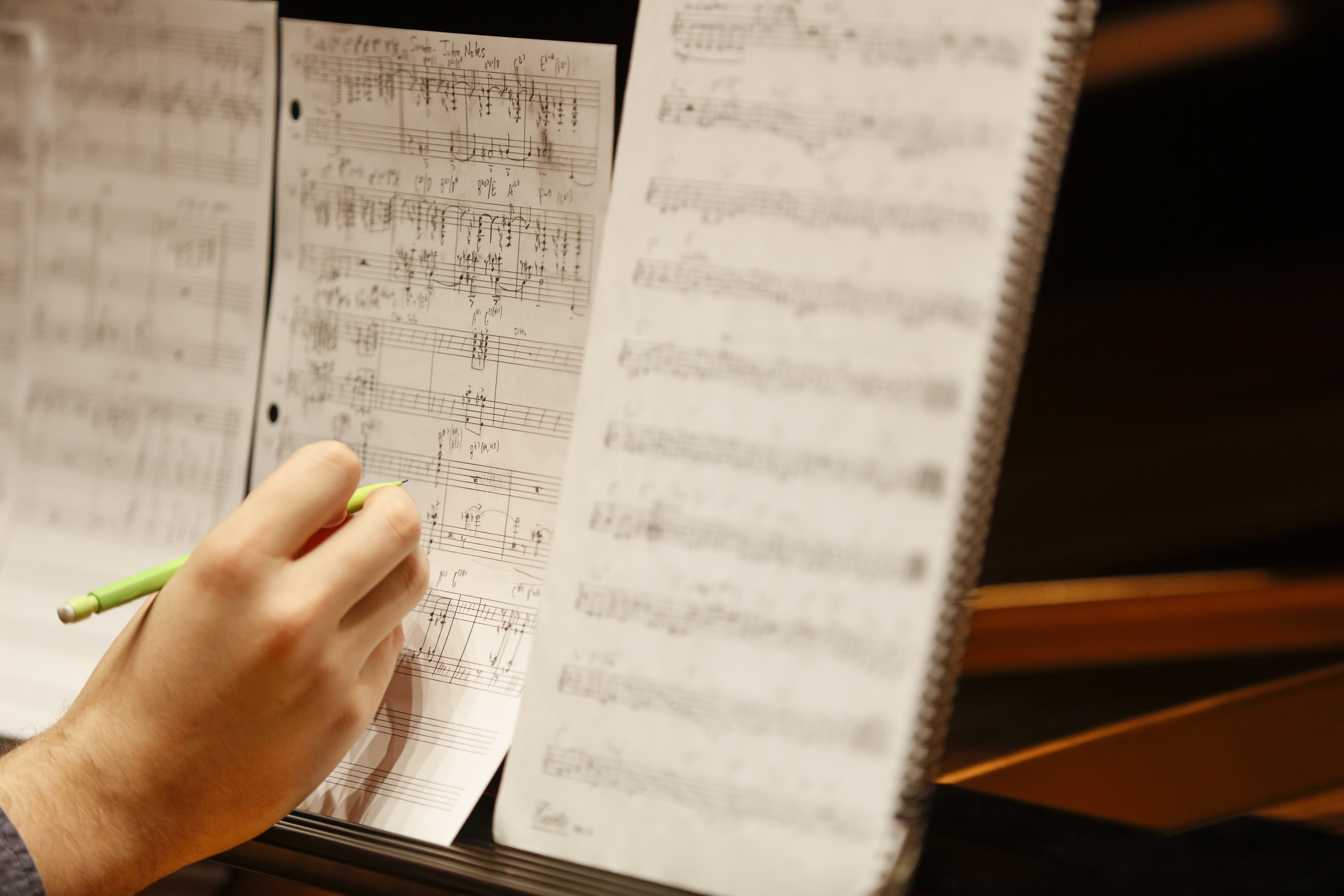 Person writing with pencil on a sheet of music.