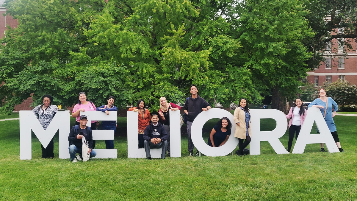 Group photo of past Fulbright Teachers at the Meliora sign on campus