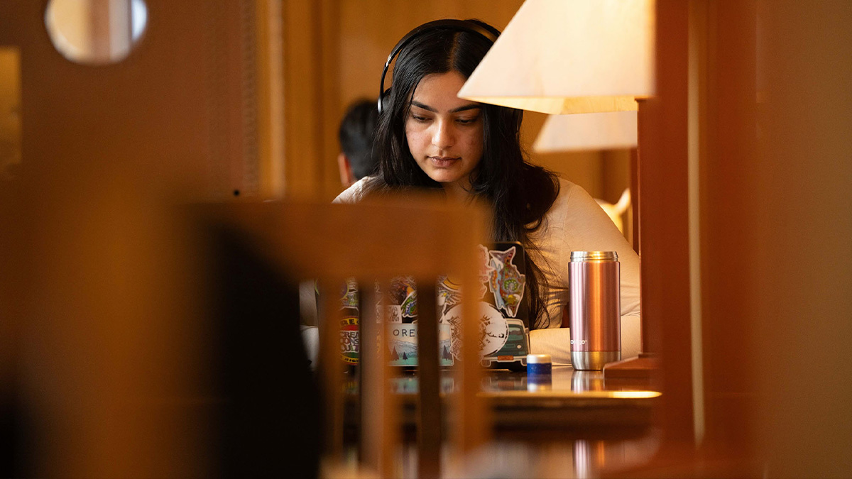 Student with headphones studying in Rush Rhess Library. (URochester photo / J. Adam Fenster)