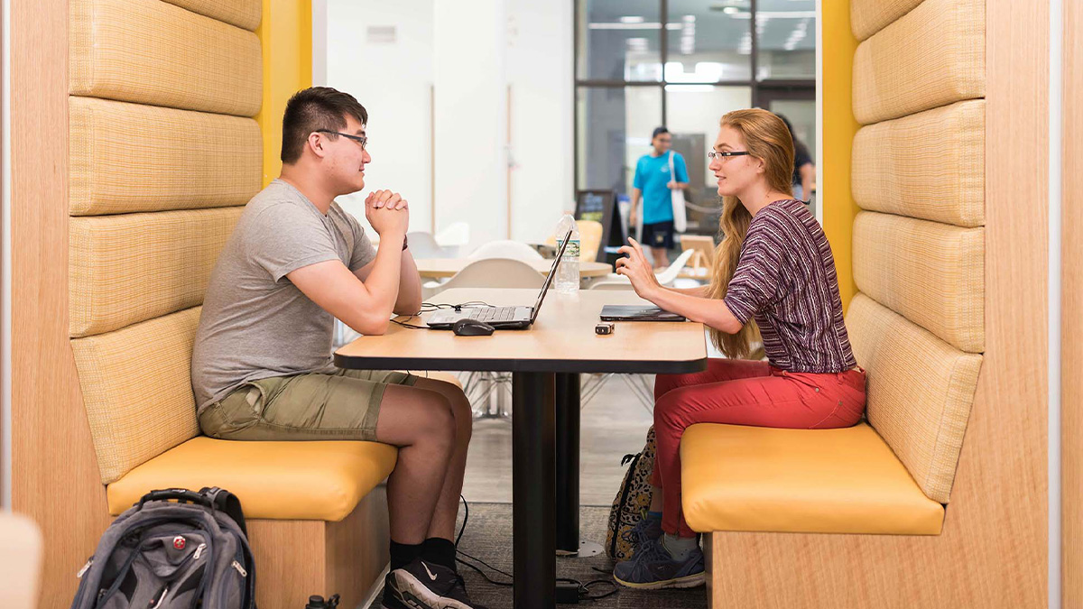 Two students working together at a booth in a study space. (URochester photo / J. Adam Fenster)