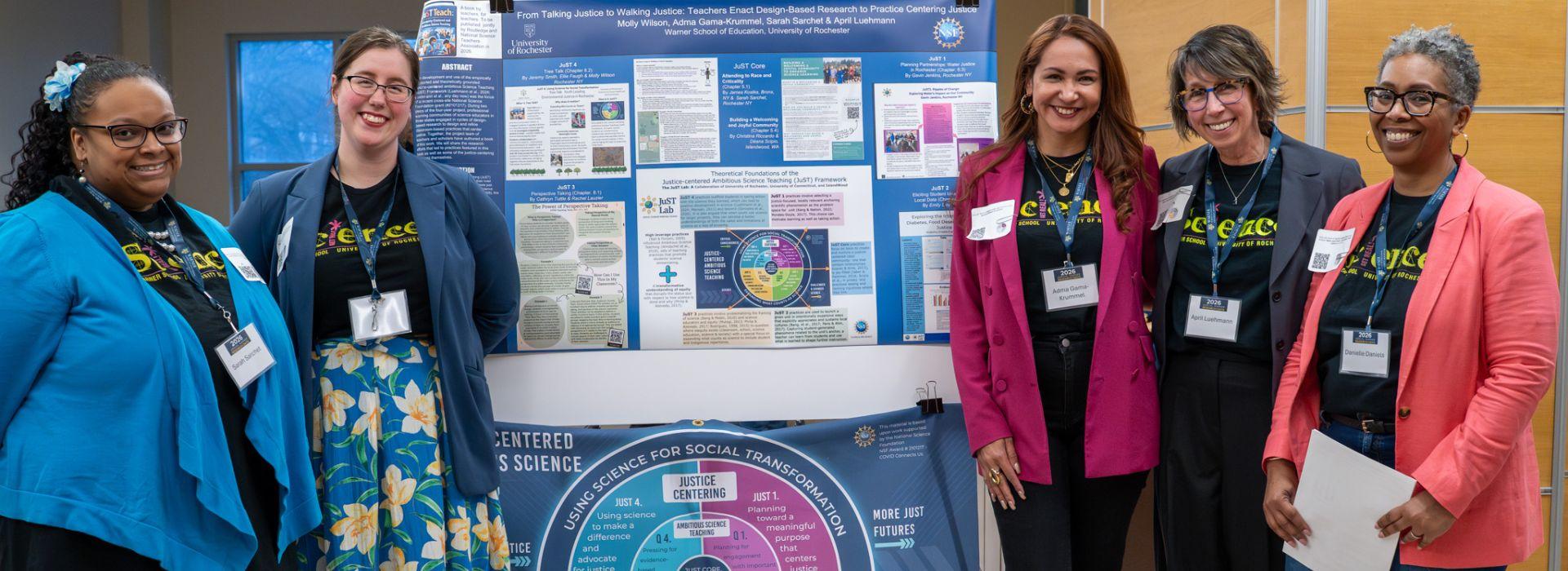 The "From Talking Justice to Walking Justice: Teachers Enact Design-Based Research to Practice Centering Justice" research group stands next to their poster presentation at the 2026 Warner Research Days event, smiling at the camera.