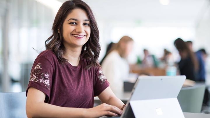 student sitting at computer and smiling