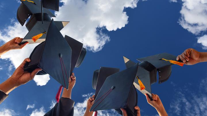 High school students holding up graduation caps.