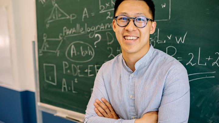Teacher smiling in front of chalk board with math equations