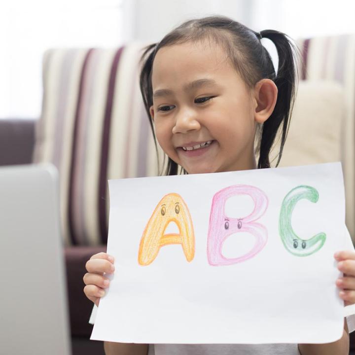 Happy child holding up ABC sign