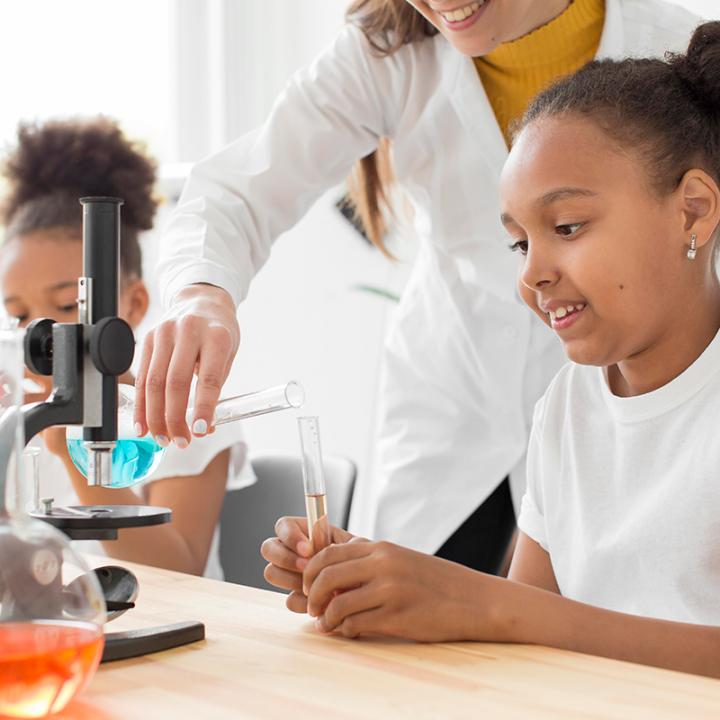 Young students in science classroom doing science lab with a teacher