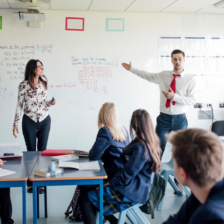 Two teacher standing in front of a class co-teaching. 