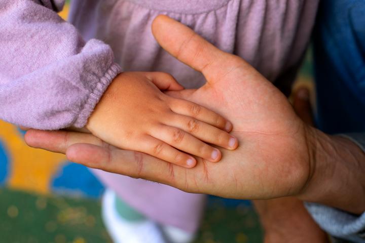 Older hand with a younger child's hand inside