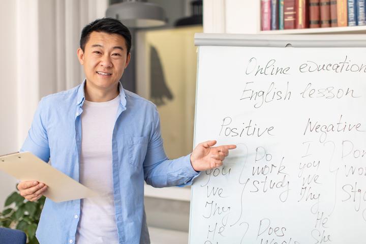 Asian man with white board that has english words