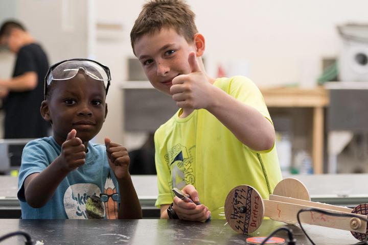 Two young kids in a STEM class giving thumbs up