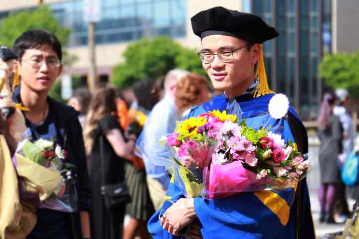 Warner graduate posing for picture holding flowers