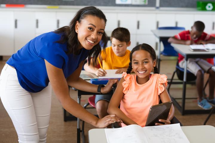Teacher and young student smiling in classroom
