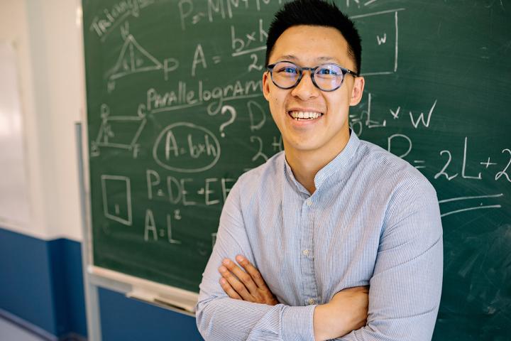 Teacher smiling in front of chalk board with math equations