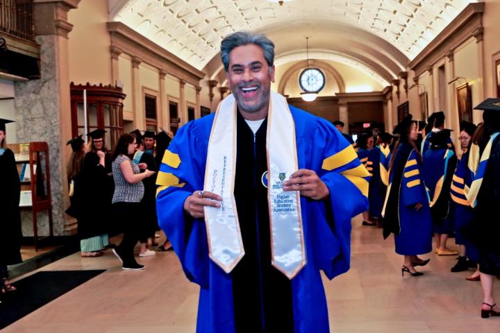 Ebby Mathew Adukkalil getting ready to accept his doctoral degree, smiling at the camera
