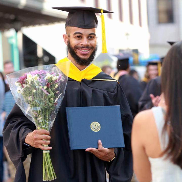 Warner graduate holding flowers and diploma