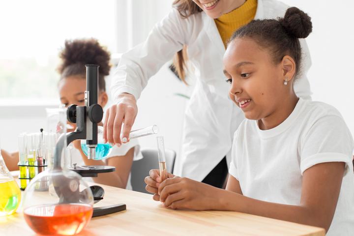 Young students in science classroom doing science lab with a teacher